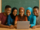 Nigerian Teenagers Urged to Leverage Technology for National Development Nigerian teenagers gathered around a laptop in a classroom, smiling and learning together.