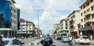 Alt Text: Bolt driver in Lagos installs a dash cam on his windshield while other ride-hailing cars queue on a busy city street, symbolizing rapid safety-tech adoption.