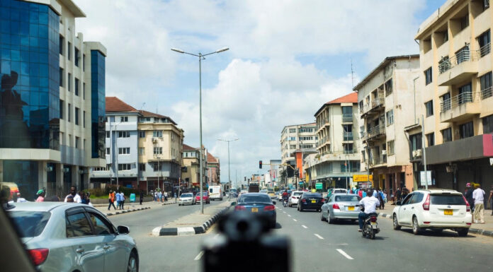 Alt Text: Bolt driver in Lagos installs a dash cam on his windshield while other ride-hailing cars queue on a busy city street, symbolizing rapid safety-tech adoption.