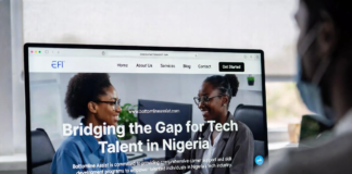 Bottomline Assist Bridges Gap for Tech Talent in Nigeria Nigerian tech founder and recruiter smiling at a large monitor displaying the Bottomline Assist platform with the headline “Bridging the Gap for Tech Talent in Nigeria” and profiles of skilled developers.