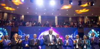 Enoch Ogunnowo Honoured at Nigeria Technology Awards 2023 Enoch Ogunnowo smiling on stage holding the Nigeria Technology Awards 2023 trophy, with bright stage lights and the NiTA logo in the background.