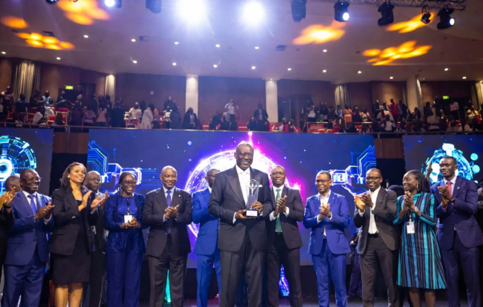 Enoch Ogunnowo Receives Top Honour at Nigeria Technology Awards 2023 Enoch Ogunnowo smiling on stage holding the Nigeria Technology Awards 2023 trophy, with bright stage lights and the NiTA logo in the background.