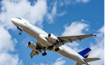 A Nigerian commercial jet taking off against a clear blue sky, with a subtle overlay of a cracked safety checklist and human silhouette, symbolising that human behaviour remains the biggest factor in aviation safety and efficiency.