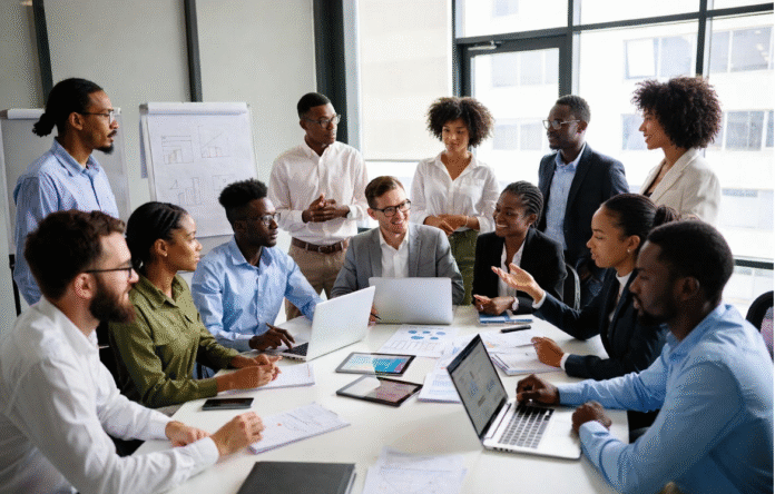 Diverse group of Nigerian tech leaders, entrepreneurs, and developers in a modern office brainstorming around laptops and data charts, symbolizing Nigeria’s ambition to lead Africa in AI innovation.