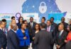 UN Women Advocates Partnerships to Tackle Digital Gender Violence UN Women representatives, Nigerian officials, and activists stand together at a Lagos summit in front of a digital Africa map with shields and locks, symbolizing the fight against online gender violence.