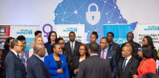 UN Women representatives, Nigerian officials, and activists stand together at a Lagos summit in front of a digital Africa map with shields and locks, symbolizing the fight against online gender violence.