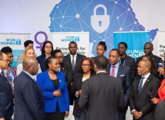 UN Women Advocates Partnerships to Tackle Digital Gender Violence UN Women representatives, Nigerian officials, and activists stand together at a Lagos summit in front of a digital Africa map with shields and locks, symbolizing the fight against online gender violence.