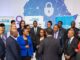 UN Women representatives, Nigerian officials, and activists stand together at a Lagos summit in front of a digital Africa map with shields and locks, symbolizing the fight against online gender violence.