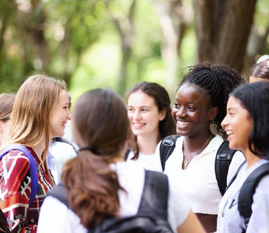 Excited Nigerian schoolgirls wearing safety goggles conducting science experiments with microscopes and test tubes during a hands-on STEM workshop at the WITIN National Summit.