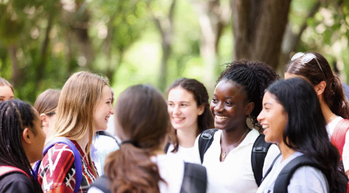 Excited Nigerian schoolgirls wearing safety goggles conducting science experiments with microscopes and test tubes during a hands-on STEM workshop at the WITIN National Summit.