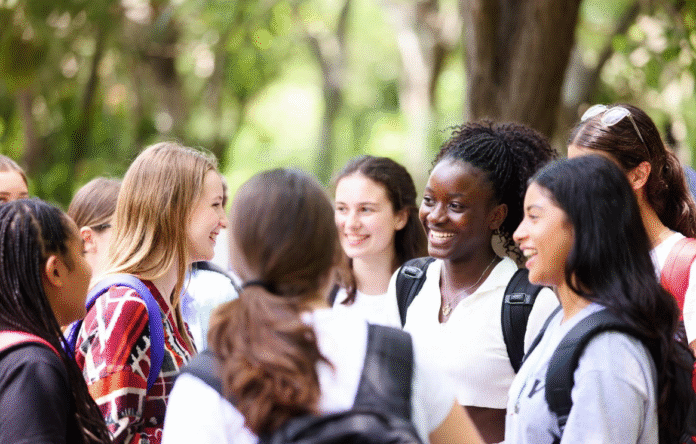 Excited Nigerian schoolgirls wearing safety goggles conducting science experiments with microscopes and test tubes during a hands-on STEM workshop at the WITIN National Summit.